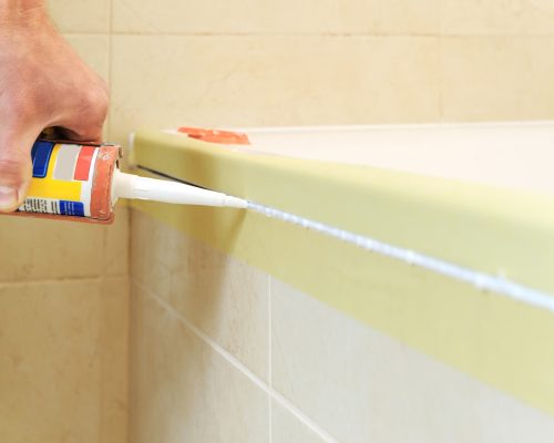 worker-puts-silicone-sealant-caulk-joint-tub-wall